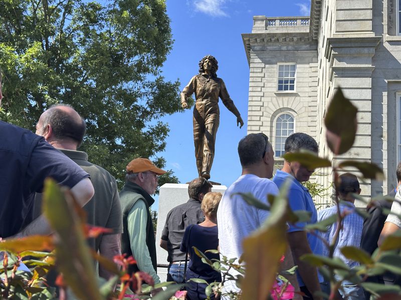 A crowd surrounds the newly-unveiled statue of Christa McAuliffe at the New Hampshire Statehouse, Monday, Sept. 2, 2024, in Concord, N.H. (AP Photo/Holly Ramer)