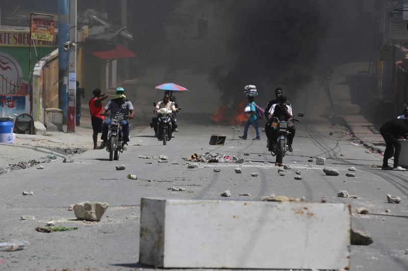 A street is blocked with burning tires and obstacles placed by protesters demanding that the police and the Prime Minister take immediate action against gangs in Port-au-Prince, Haiti, Monday, Aug. 19, 2024. (AP Photo/Odelyn Joseph)