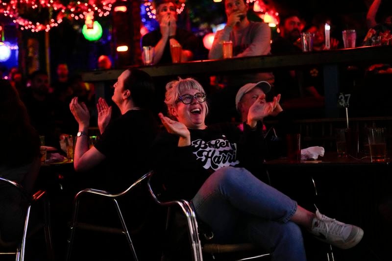 Amy Pottinger, wearing a Biden/Harris sweatshirt, claps as President Joe Biden comments on how Republican presidential candidate former President Donald Trump handled January 6th as people watch the presidential debate at Hula Hula, a tiki themed bar, Thursday, June 27, 2024, in Seattle. (AP Photo/Lindsey Wasson)