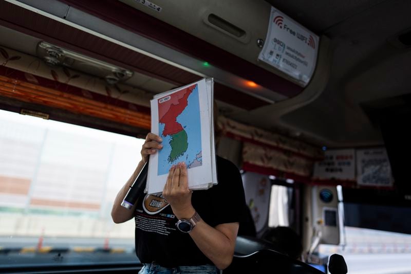 A tour guide holds a map while explaining the Korean War to tourists on a bus heading to Imjingak Pavilion in Paju, South Korea, Saturday, May 25, 2024. (AP Photo/Jae C. Hong)