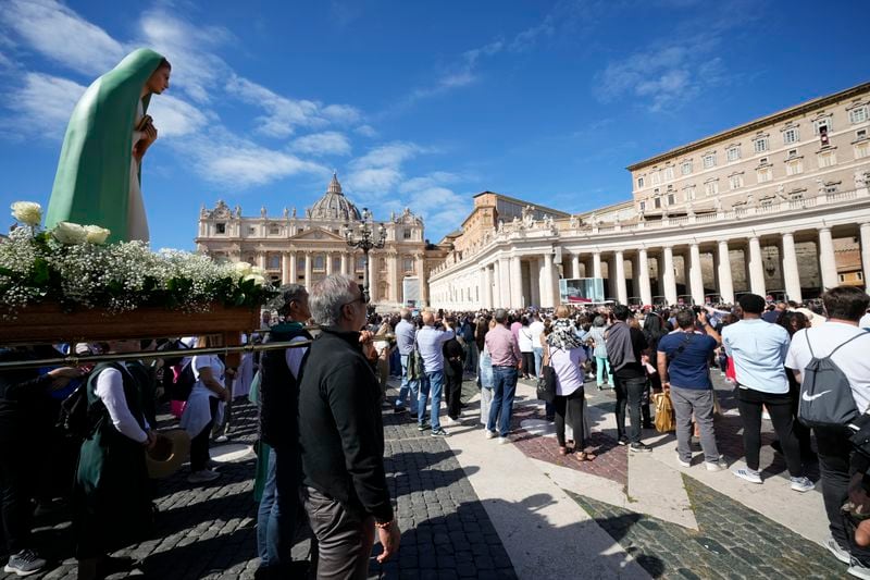 A statue of the Virgin Mary is carried in St. Peter's Square at The Vatican while Pope Francis appears at the window of his studio for the traditional noon blessing of faithful and pilgrims, Sunday, Oct. 6, 2024. (AP Photo/Andrew Medichini)