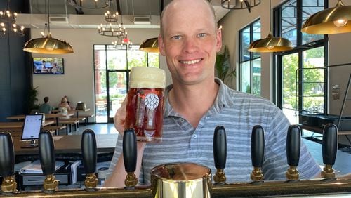 CEO Craig Mycoskie hoists a beer at Round Trip Brewing's Marietta taproom. (Bob Townsend for The Atlanta Journal-Constitution)