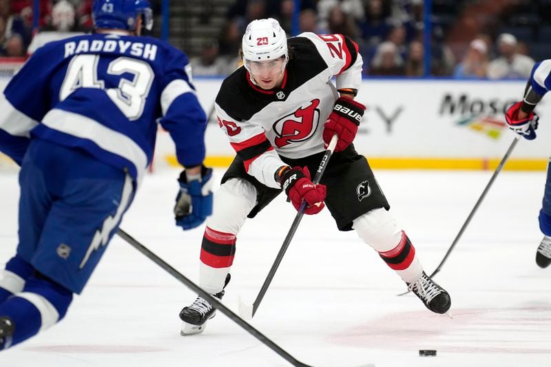 FILE - New Jersey Devils center Michael McLeod (20) carries the puck against Tampa Bay Lightning defenseman Darren Raddysh (43) during the first period of an NHL hockey game Jan. 11, 2024, in Tampa, Fla. Four current members of the National Hockey League charged with sexual assault in Canada will become free agents after not receiving qualifying offers from their respective teams. Carter Hart was under contract with Philadelphia, McLeod and Cal Foote with New Jersey and Dillon Dube with Calgary when they were charged in connection with an incident that occurred in London, Ontario, in 2018 after they were teammates on Canada's world junior team. (AP Photo/Chris O'Meara, File)