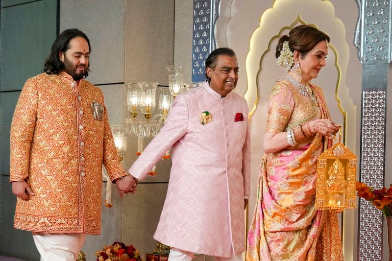 Billionaire Mukesh Ambani, center, takes his son Anant Ambani by the hand as they walk with Neeta Ambani, right, at the wedding of Anant and Radhika Merchant at Jio World Convention Centre in Mumbai, India, Friday, July 12, 2024. (AP Photo /Rajanish Kakade)