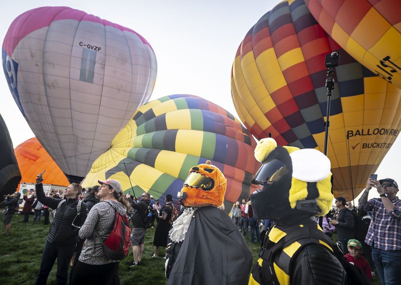 Matt Ramos, center, and his girlfriend Alana Mariah of Albuquerque broadcast a live video stream while wearing costumes during the mass ascension at the 52nd Albuquerque International Balloon Fiesta in Albuquerque, N.M., on Saturday, Oct. 5, 2024. (AP Photo/Roberto E. Rosales)