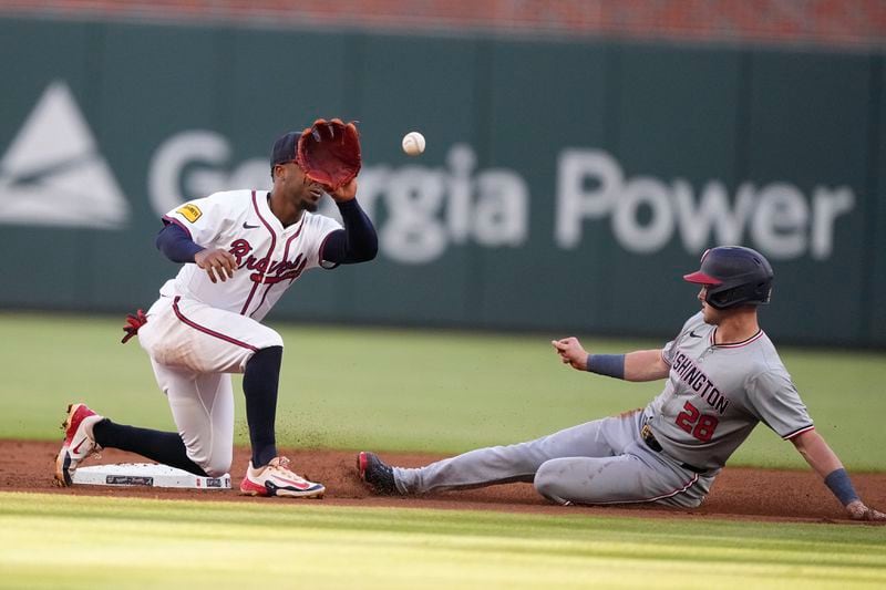 Washington Nationals outfielder Lane Thomas (28) steals second base against Atlanta Braves second base Ozzie Albies (1) in the first inning of a baseball, Thursday, May 30, 2024, in Atlanta. (AP Photo/Brynn Anderson)