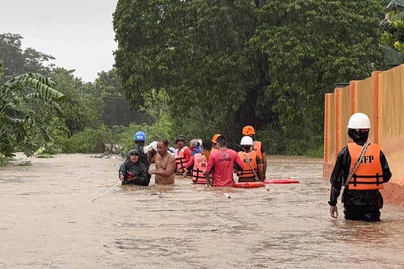 Rescuers help residents as they negotiate floods caused by powerful Typhoon Krathon locally called "Typhoon Julian" at Bacarra, Ilocos Norte province, northern Philippines on Monday, Sept. 30, 2024. (AP Photo/Bernie Dela Cruz)