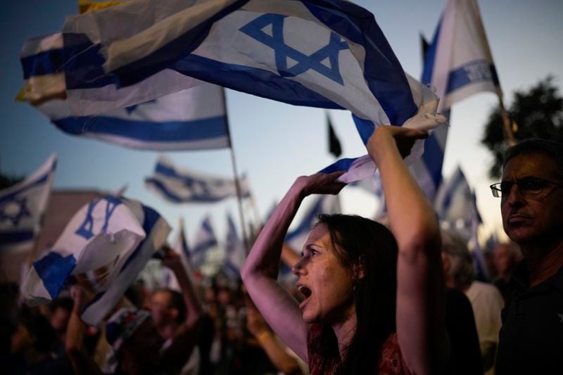 People wave Israeli flags during a protest against Israeli Prime Minister Benjamin Netanyahu's government and demanding elections outside of the Knesset, Israel's parliament, in Jerusalem, Tuesday, June 18, 2024. (AP Photo/Leo Correa)