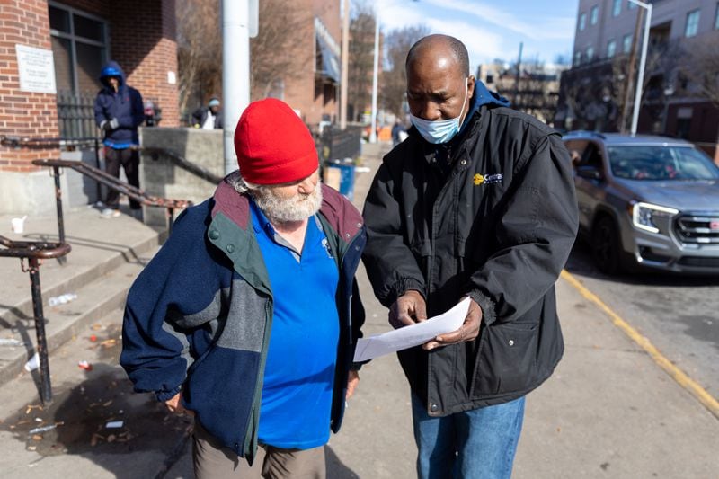 Siegfried Darcell White (right), with Concerned Dads and Not on My Watch Ministry, shows Michael Cumbie (left) a list of shelters in front of Gateway Center in Atlanta on Tuesday, January 16, 2024. (Arvin Temkar / arvin.temkar@ajc.com)