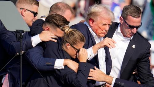 Republican presidential candidate former President Donald Trump is helped off the stage by U.S. Secret Service agents at a campaign event in Butler, Pa., on Saturday, July 13, 2024. (AP Photo/Gene J. Puskar)
