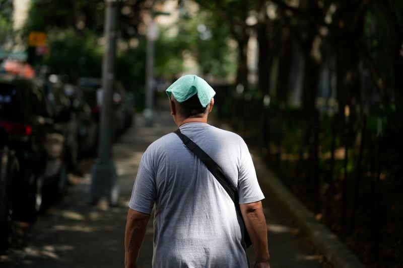 FILE - A man wears a damp towel on his head during a hot day in New York, Tuesday, July 16, 2024. (AP Photo/Seth Wenig, File)