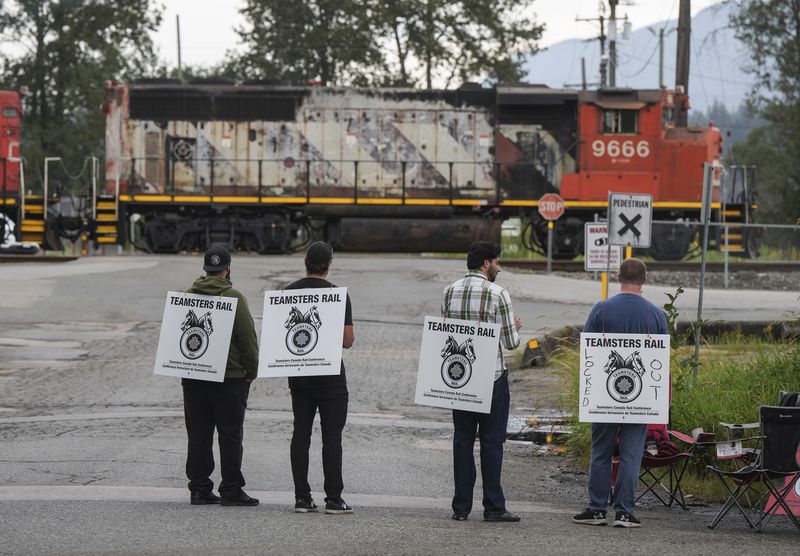 Locked out Canadian National Rail workers stand at a picket line as locomotives are moved by management at CN Rail's Thornton Yard in Surrey, British Columbia, Canada, Thursday, Aug. 22, 2024. (Darryl Dyck/The Canadian Press via AP)