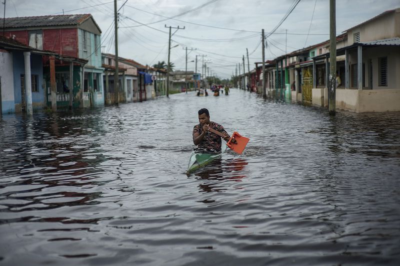 A man in a kayak uses a makeshift paddle as he travels through a street flooded in the passing of Hurricane Helene, in Batabano, Mayabeque province, Cuba, Thursday, Sept. 26, 2024. (AP Photo/Ramon Espinosa)