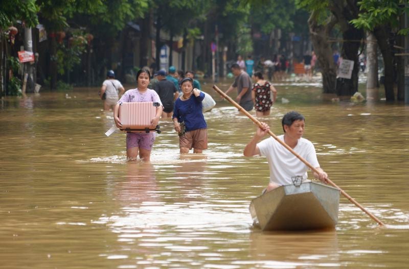 People carrying belongings wade in a flooded street in the aftermath of Typhoon Yagi, in Hanoi, Vietnam on Thursday, Sep. 12, 2024. (AP Photo/Hau Dinh)