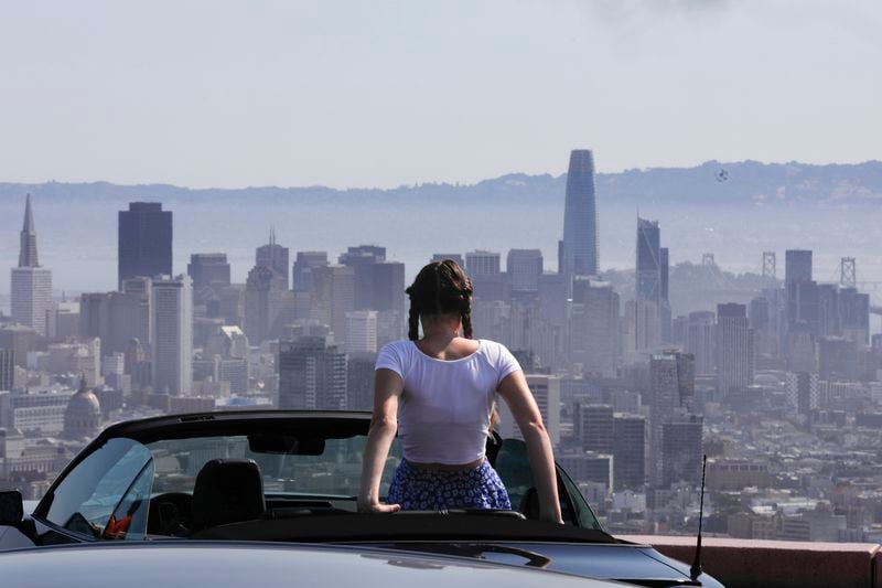 Lilou Guerra, 16, of France is dressed for sunny weather during a heat wave while she takes in the view of San Francisco, while visiting Twin Peaks with her parents on Wednesday, July 3, 2024. (Lea Suzuki/San Francisco Chronicle via AP)