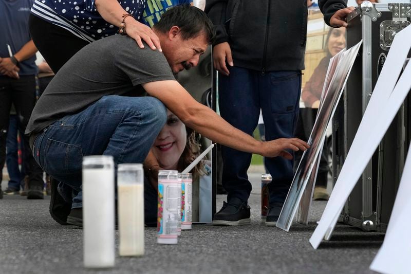 Daniel Delgado reaches to touch a photo of his wife, Monica Hernandez, who died at Impact Plastics during flooding caused by Hurricane Helene, at a vigil for victims of the tragedy in Erwin, Tenn., on Thursday, Oct. 3, 2024. (AP Photo/Jeff Roberson)