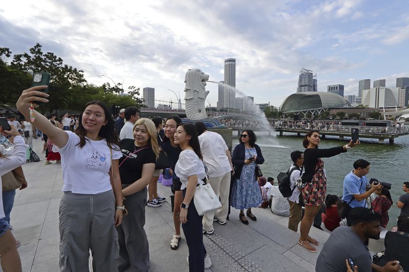 People take photos at Merlion Park in Singapore, Saturday, Sept. 7, 2024. (AP Photo/Suhaimi Abdullah)