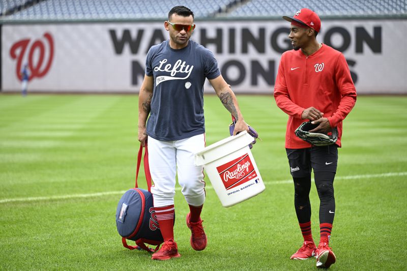 Washington Nationals first base coach Gerardo Parra, left, walks off the field with Nationals' Darren Baker after Parra conducted outfield practice before a baseball game against the Chicago Cubs, Sunday, Sept. 1, 2024, in Washington. (AP Photo/John McDonnell)