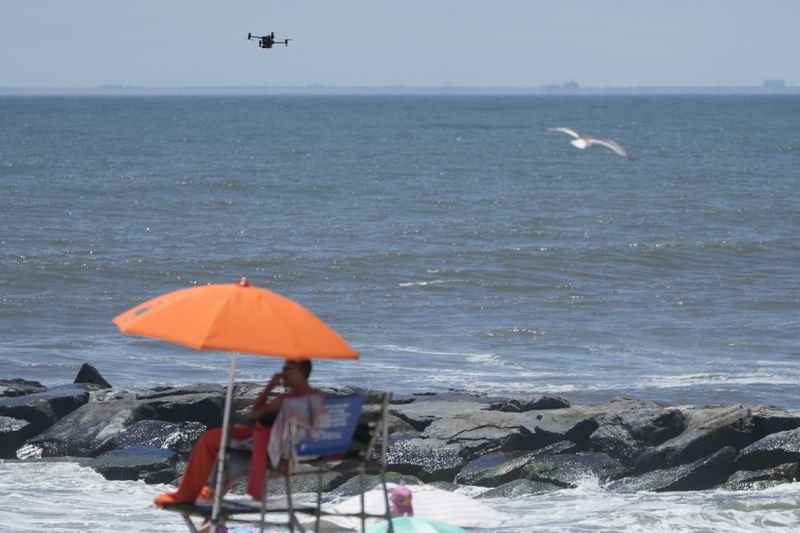 A drone scans the shoreline for signs of struggling swimmers, sharks and other hazards at Rockaway Beach in New York, Thursday, July 11, 2024. A fleet of drones patrolling New York City’s beaches for signs of sharks and struggling swimmers is drawing backlash from an aggressive group of seaside residents: local shorebirds. Since the drones began flying in May, flocks of birds have repeatedly swarmed the devices, forcing the police department and other city agencies to adjust their flight plans. (AP Photo/Seth Wenig)
