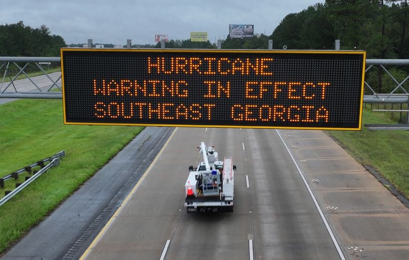 A utility truck passes under a hurricane warning sign on I-75 near Adel on Thursday.