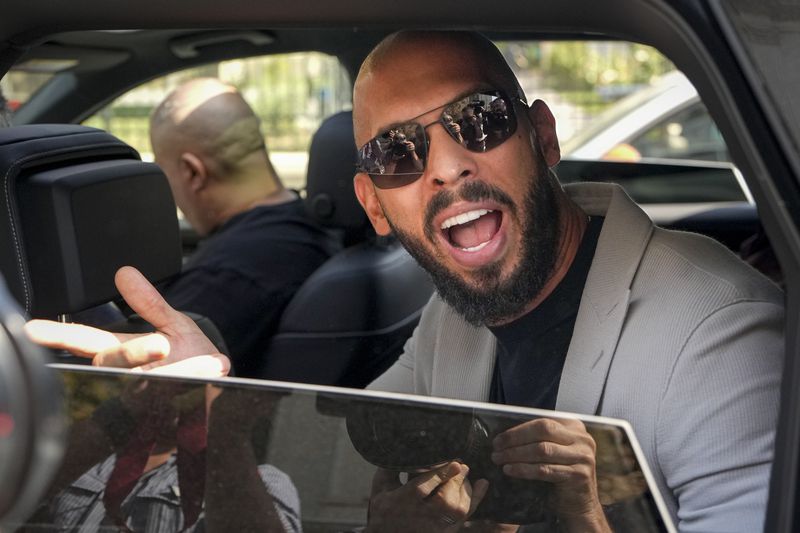 Andrew Tate sits in a car and talks to reporters surrounding his car after exiting the Court of Appeals building, after a hearing, in Bucharest, Romania, Wednesday, Sept. 4, 2024. (AP Photo/Vadim Ghirda)