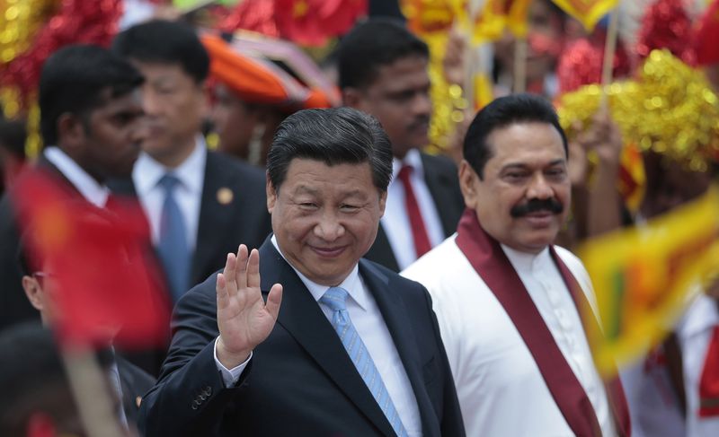 FILE - China's President Xi Jinping, left, waves as he walks with then Sri Lankan President Mahinda Rajapaksa upon arrival at the airport in Colombo, Sri Lanka, Sept. 16, 2014. (AP Photo/Eranga Jayawardena, File)