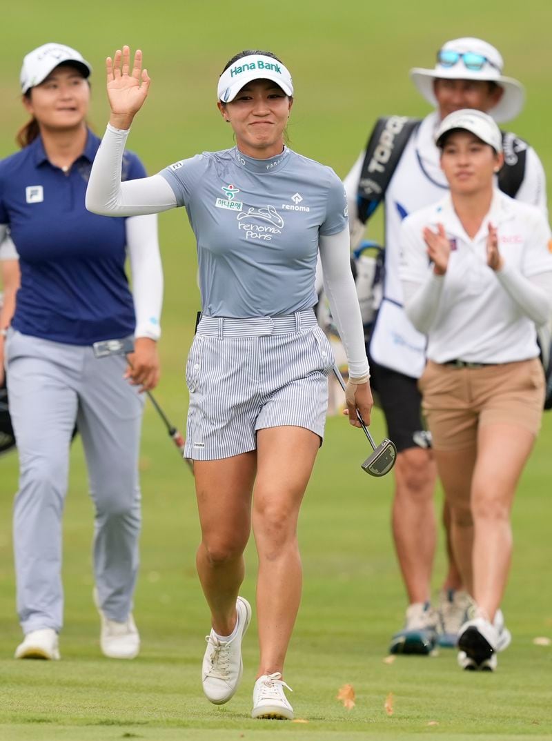 Lydia Ko, center, of New Zealand, center, waves to a cheering crowd as she walks to the 18th hole, followed by Yan Liu, left, of China, and Jeeno Thitikul, front right, of Thailand, during the final round of the LPGA Kroger Queen City Championship golf tournament at TPC River's Bend in Maineville, Ohio, Sunday, Sept. 22, 2024. (AP Photo/Carolyn Kaster)