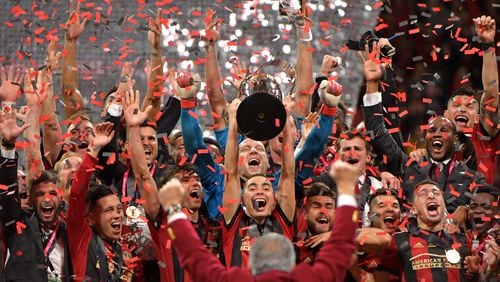 Atlanta United midfielder Miguel Almiron raises the MLS Cup as the team celebrates after its 2-0 win over the Portland Timbers during the 2018 MLS Cup at Mercedes-Benz Stadium in 2018. (HYOSUB SHIN file photo / HSHIN@AJC.COM)