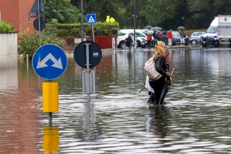 Two women wade through floodwater caused by heavy rain in a street in Milan, Italy, Thursday Sept. 5, 2024. (Stefano Porta/LaPresse via AP)