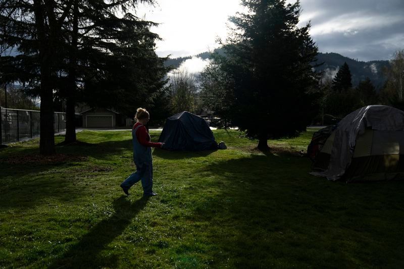 FILE - Cassy Leach, a nurse who leads a group of volunteers who provide food, medical care and other basic goods to the hundreds of homeless people living in the parks, walks to help homeless people camping in Fruitdale Park move their tents, March 23, 2024, in Grants Pass, Ore. On Friday, June 28, the Supreme Court ruled that cities can enforce bans on homeless people sleeping outdoors in West Coast areas where shelter space is lacking. (AP Photo/Jenny Kane, File)