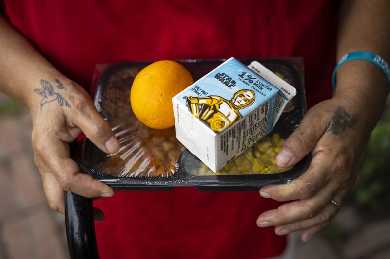 Elizabeth Flores holds up her Meals on Wheels delivery, Friday, July 12, 2024, in Houston. (AP Photo/Annie Mulligan)