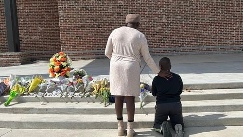 Cecil Oduory and her 10-year-old son, Dylan Cheruiyot, brought flowers to Jug Tavern Park to honor those killed in last week's shooting. (Martha Dalton/The Atlanta Journal-Constitution)