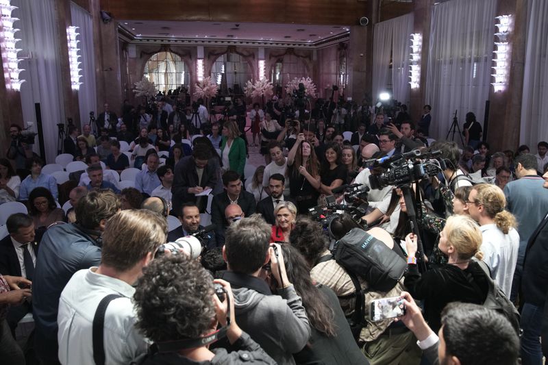 French far-right leader Marine Le Pen, center in red, and conservative politician Eric Ciotti, center left partially obscured, arrive to attend a press conference by far-right National Rally party president Jordan Bardella, Monday, June 24, 2024 in Paris. The upcoming two-round parliamentary election will take place on June 30 and July 7. (AP Photo/Christophe Ena)