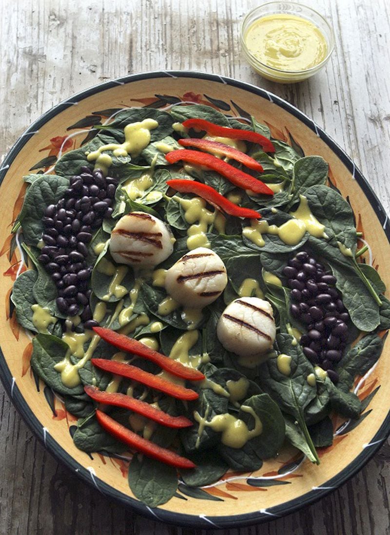 A mango vinaigrette dresses a salad of spinach, black beans, red peppers and scallops. (Hillary Levin/St. Louis Post-Dispatch/TNS)