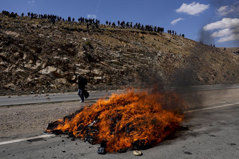 An effigy of former President Evo Morales is engulfed in flames on the road between Caracollo and La Paz, the route Morales' supporters are using to march to the capital against the government of President Luis Arce, in an escalation of a political dispute between the two politicians, Tuesday, Sept. 17, 2024. (AP Photo/Juan Karita)