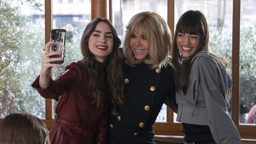 In this his handout photo taken by Stephanie Branchu for Netflix on April 2, 2024, in Paris, Lily Collins, left, French President Emmanuel Macron's wife Brigitte Macron, center, and Thalia Besson pose for a selfie during the shooting of episode 407 of Netflix series "Emily in Paris". (Netflix via AP)