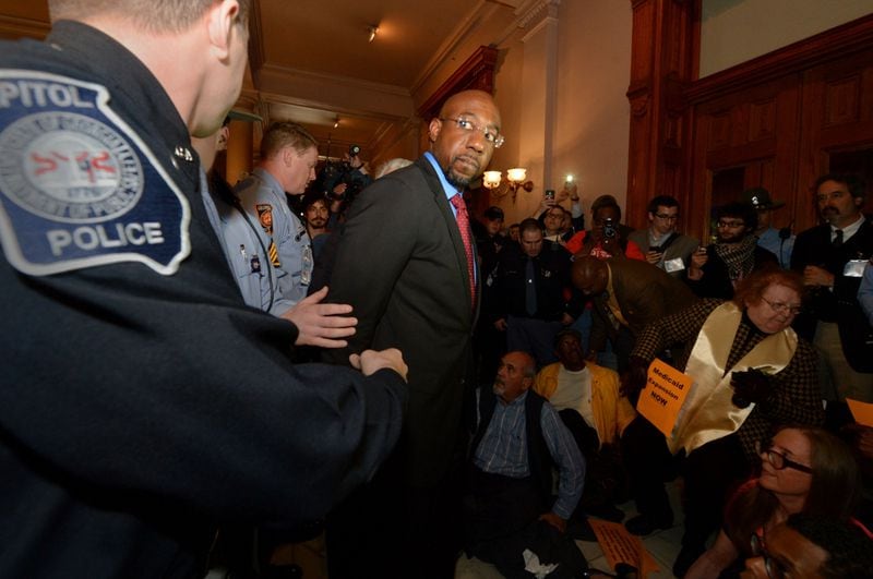 The Rev Raphael Warnock is arrested in front of the governor's office at the Georgia Capitol during a rally in 2014. Since becoming the pastor of Atlanta's Ebenezer Baptist Church, Warnock has led voter registration drives, advocated for the expansion of Medicaid, hosted a climate change summit with Al Gore, opposed capital punishment and pushed for an overhaul of criminal justice policy. KENT D. JOHNSON / KDJOHNSON@AJC.COM