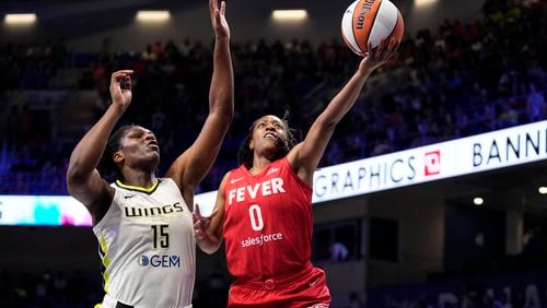 Indiana Fever's Kelsey Mitchell (0) leaps to the basket to take a shot as Dallas Wings' Teaira McCowan (15) defends in the first half of a WNBA basketball game Wednesday, July 17, 2024, in Arlington, Texas. (AP Photo/Tony Gutierrez)