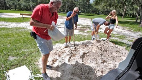 Roger Heim, left, and Terry Smith, second from left, both of Valrico, Fla., fill sand bags in preparation for a weekend storm at the Edward Medard Conservation Park in Plant City, Fla. AP Photo/Chris O'Meara)
