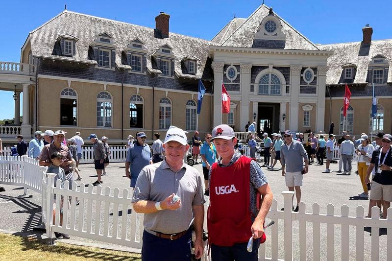 Frank Bensel, left, and his caddie and 14-year-old son, Hagen, pose in front of the clubhouse after Bensel turned up a pair of aces on the back-to-back holes during the second round of the U.S. Senior Open golf tournament in Newport, R.I., Friday, June 28, 2024. (AP Photo/Jimmy Golen)