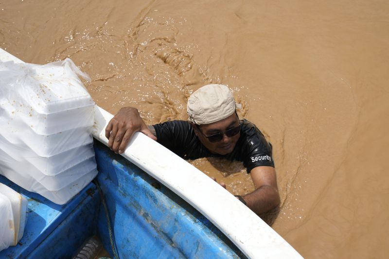 Local residents carrying food wade through a flooded road in Naypyitaw, Myanmar, Saturday, Sept. 14, 2024. (AP Photo/Aung Shine Oo)