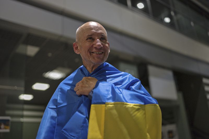 Priest Bohdan Heleta, who was detained inside his own church in the occupied city of Berdiansk in the Zaporizhzhia region in 2022, smiles at Kyiv airport in Kyiv, Ukraine, Saturday, June 29, 2024. Ten Ukrainians who had been held prisoners for years, were released from Russian captivity on Friday with a mediation of Vatican, said Ukraine's president Volodymyr Zelenskyy. (AP Photo/Alex Babenko)