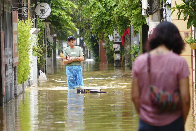 People wade in a flooded street in the aftermath of Typhoon Yagi, in Hanoi, Vietnam on Thursday, Sept. 12, 2024. (AP Photo/Hau Dinh)