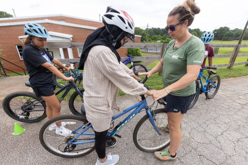 Instructor Ashley Clarkin helps participants set their bikes up properly before the start of their first bike riding lesson in Decatur Saturday. July 23, 2023.  (Steve Schaefer/steve.schaefer@ajc.com)