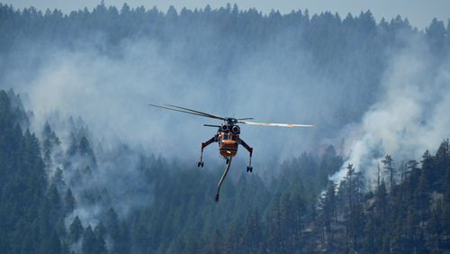 A helicopter looks to make a drop of water as the Quarry wildfire burns in the foothills near the Ken Caryl Ranch development Thursday, Aug. 1, 2024, southwest of Litteton, Colo. (AP Photo/David Zalubowski)