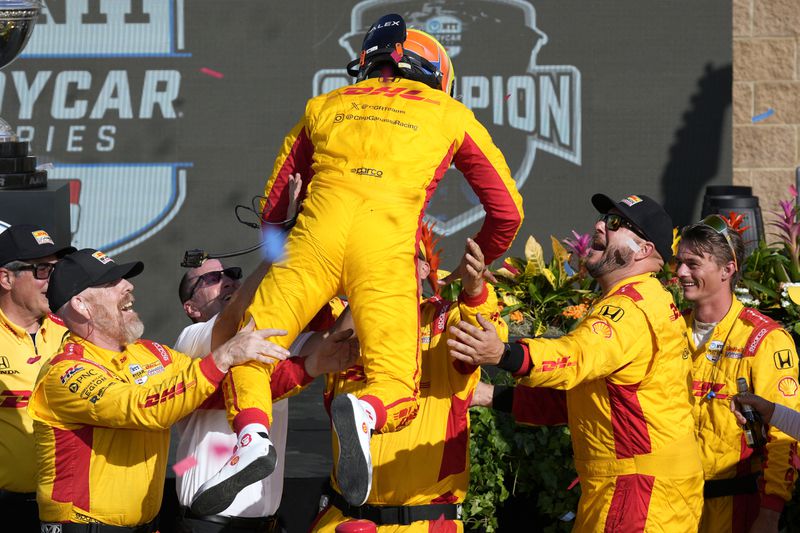 Alex Palou jumps onto his crew members after winning his third IndyCar championship in four years Sunday, Sept. 15, 2024, at Nashville Superspeedway in Lebanon, Tenn. (AP Photo/Mark Humphrey)