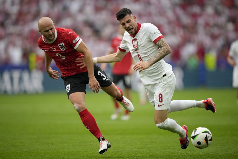 Poland's Jakub Moder, right, and Austria's Gernot Trauner fight for the ball during a Group D match between Poland and Austria at the Euro 2024 soccer tournament in Berlin, Germany, Friday, June 21, 2024. (AP Photo/Ebrahim Noroozi)