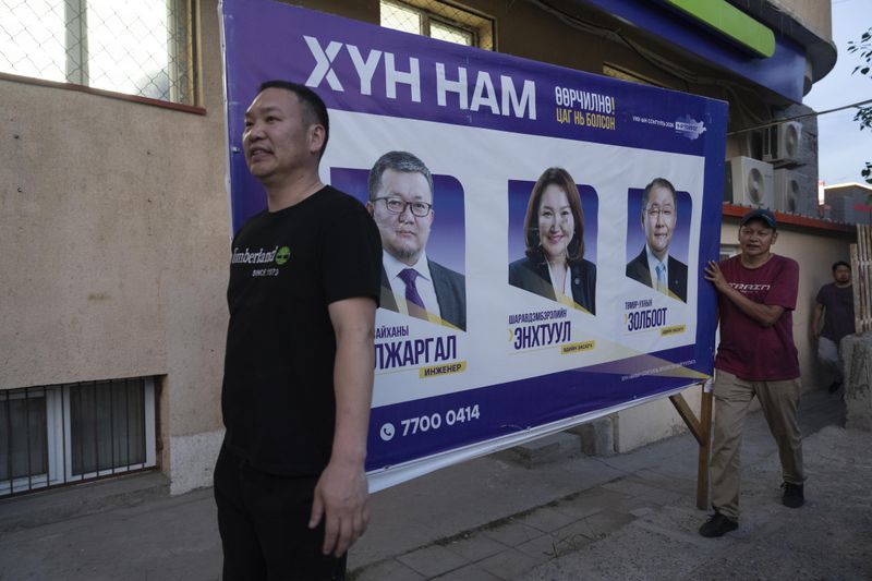 Workers remove publicity poster two days before polls open in Ulaanbaatar, Mongolia on Wednesday, June 26, 2024. A parliamentary election will be held in Mongolia on Friday, June 28, 2024 for the first time since the body was expanded to 126 seats. (AP Photo/Ng Han Guan)