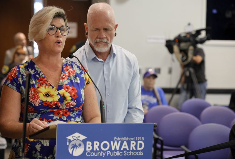 Jessica Norton, with her husband, Gary, speaks during the public comment period at a Broward County School Board meeting in Fort Lauderdale, Fla., Tuesday, June 18, 2024. Norton, whose daughter played on the Monarch High School volleyball team, was one of five Monarch officials removed from the school Nov. 27 amid an inquiry into possible violations of the "Fairness in Women's Sports Act," a 2021 law that bans transgender girls from playing on girls' sports teams. Norton is the only one facing potential discipline. (Amy Beth Bennett/South Florida Sun-Sentinel via AP)