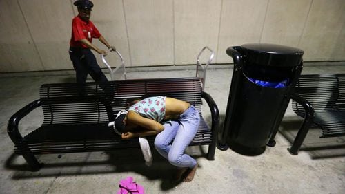 After most flights have concluded for the night a woman sleeps on the bench outside the south baggage claim at Hartsfield-Jackson Atlanta International Airport on Tuesday, Oct. 1, 2013, in Atlanta.